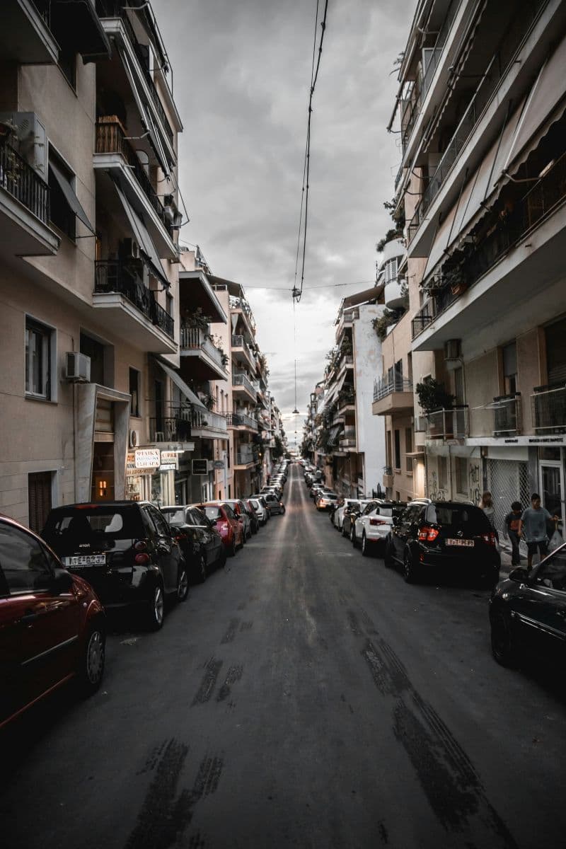 Narrow city street with parallel parked cars on both sides
