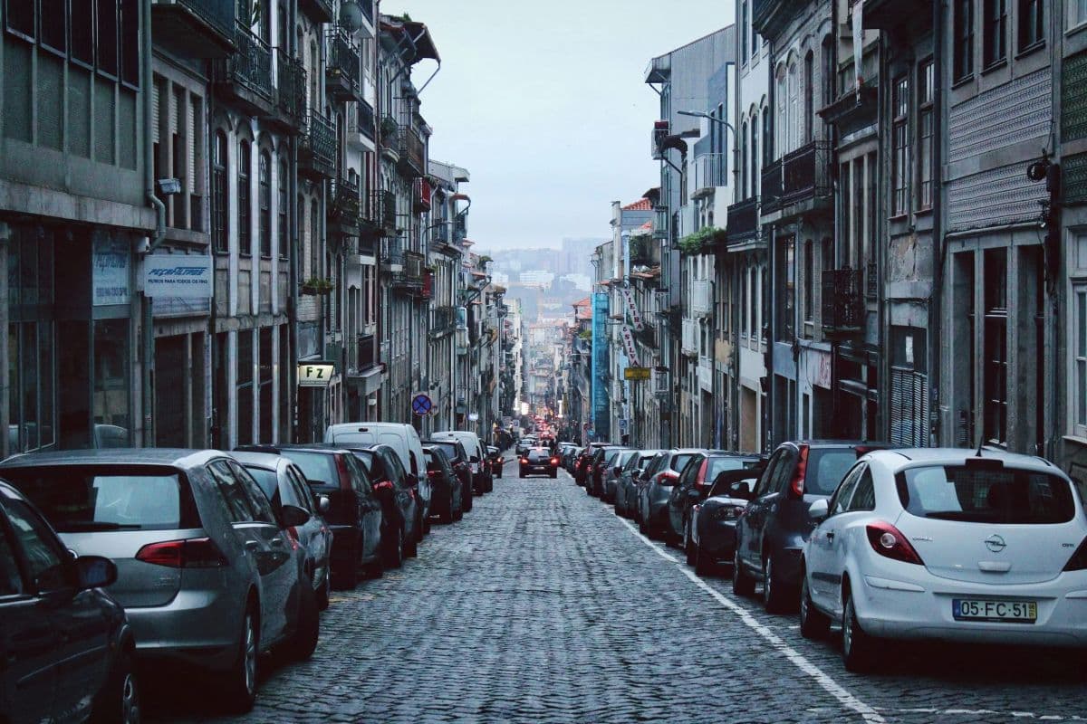 Steep cobblestone street lined with parallel parked cars